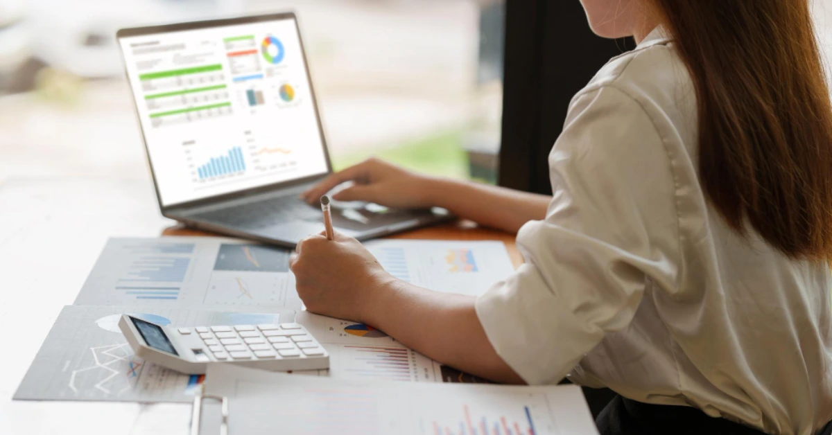 como estudar para concursos fiscais Mulher verificando dados em folhas impressas e notebook para ilustrar como estudar para concursos fiscais.
