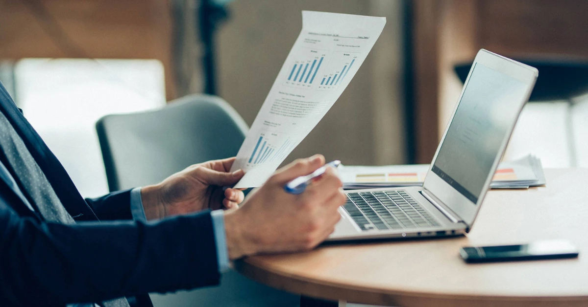concursos fiscais como se preparar concursos fiscais: home de terno estudando gráficos sobre a mesa.