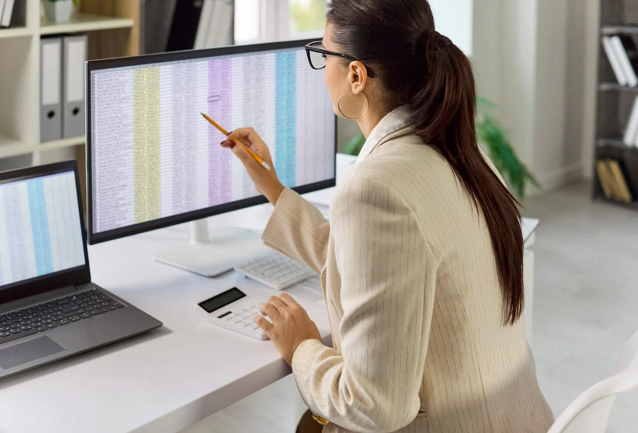 curso para concurso auditor fiscal mulher de terno verificando planilha no computador para ilustrar curso para concurso auditor fiscal.